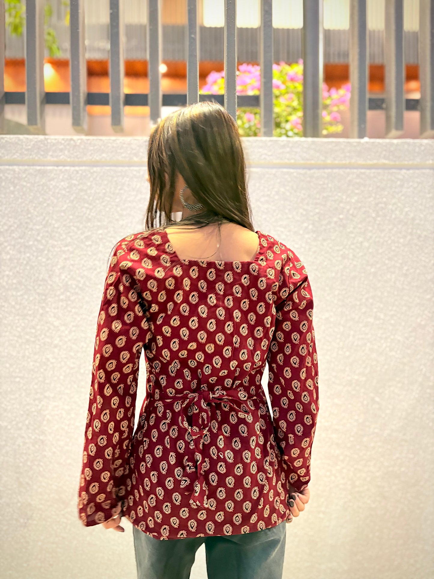 Girl wearing maroon paisley print fitted top with tie-waist detail