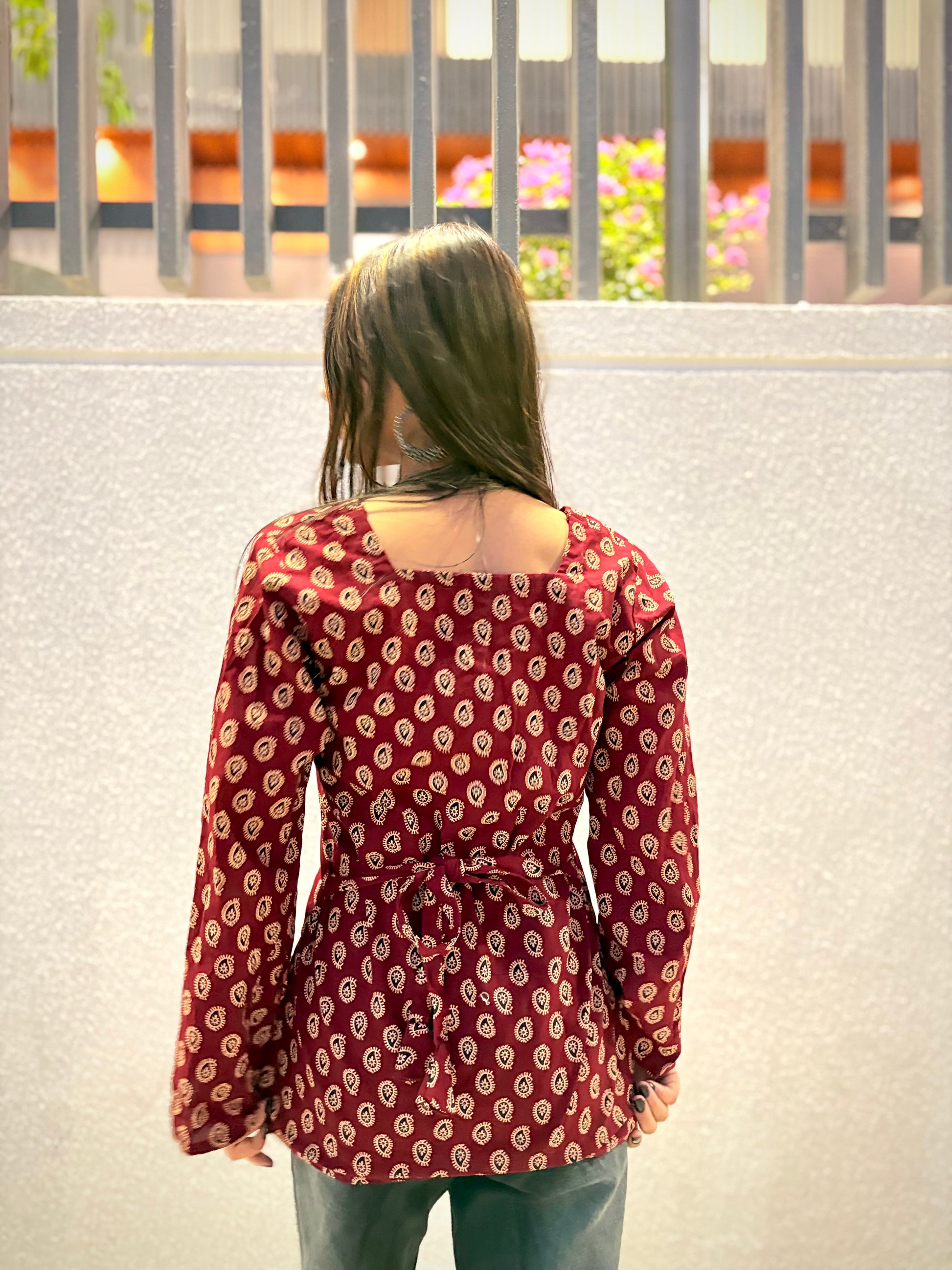 Girl wearing maroon paisley print fitted top with tie-waist detail
